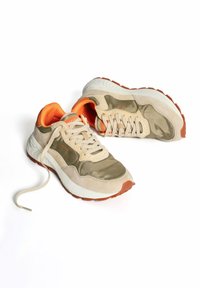 Zapatillas beige y verde olivo con acentos naranjas, que cuentan con una parte superior texturizada, cuello acolchado y una suela de goma con un dibujo estampado.