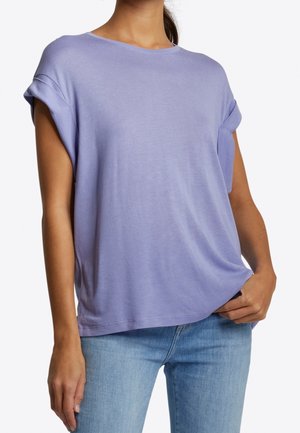 T-shirt lilas clair à manches courtes avec revers roulés et coupe décontractée. Matière douce, design simple et col rond. Associé à un jean bleu.