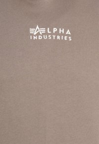 Chemise en coton grise avec un petit logo blanc "Alpha Industries". Texture lisse avec un col rond.