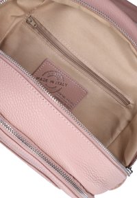 Interno di una borsa in pelle rosa con una superficie testurizzata, dotato di una tasca con cerniera e un'etichetta "Made in Italy" su una fodera in tessuto beige.