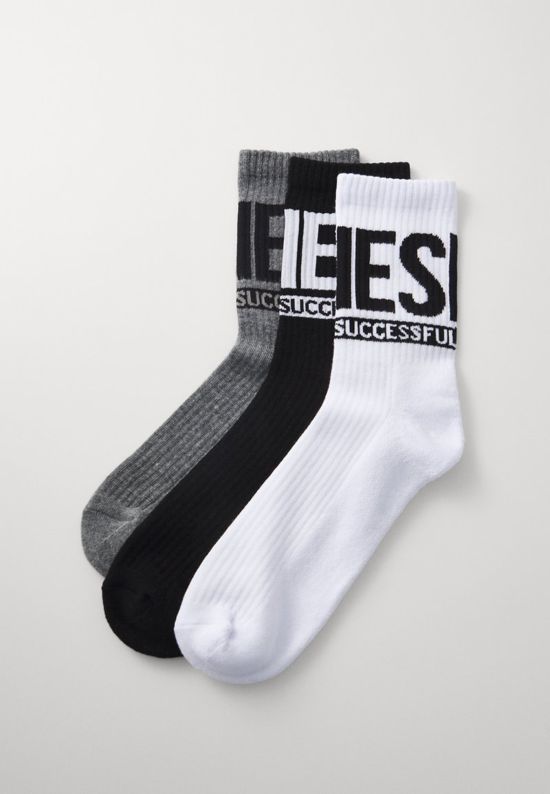 Tres pares de calcetines de tripulación en gris, negro y blanco. Cada calcetín presenta una textura acanalada y letras en negrita "EXITOSO" en los puños.