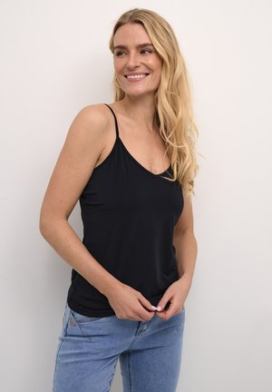 Débardeur noir sans manches avec un design en V, fabriqué dans un tissu lisse. Le mannequin porte un jean bleu clair, tenant le bas du top.