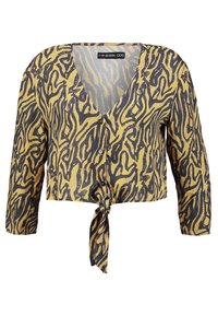 Cropped button-up blouse in black and golden animal print, featuring long sleeves and a tied front hem. Made from lightweight fabric.