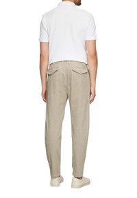 Beige corduroy broek met een relaxte pasvorm, voorzien van twee achterzakken en een tailleband, gecombineerd met een witte polo met korte mouwen.