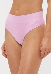 High-waisted pink underwear made of smooth fabric, featuring a seamless design and a minimalist shape without visible stitching.