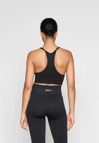 Svart aktivt treningstøy sett som inneholder en teksturert, tettsittende crop-top med racerback design og høy midje leggings. Merkevare synlig på livet.