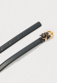 Črn usnjen pas z teksturirano površino, zlat ton okrogle zaponke z abstraktnim dizajnom in več prilagoditvenimi luknjami.