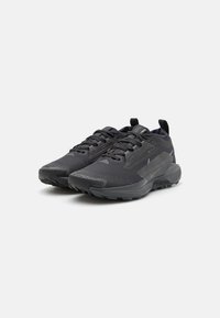 Chaussures de sport noires avec une tige en maille et des superpositions texturées. Elles présentent des lacets, une semelle en caoutchouc et un embout renforcé pour la durabilité.
