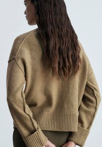 Brauner, verkürzter Pullover aus weichem Strickstoff mit geripptem Saum und Bündchen sowie überschnittenen Schulternähten. Mit einer glatten Oberfläche strukturiert.
