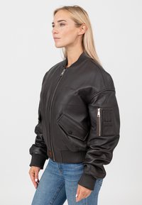 Czarna skórzana kurtka bomber z ryflowanymi mankietami i dołem, z zamek błyskawicznym z przodu, bocznymi kieszeniami oraz kieszenią na ramię z zamkiem.