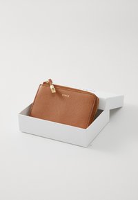 Braune Lederbörse mit strukturierter Oberfläche, ausgestattet mit einem goldenen Reißverschluss und Zugband, präsentiert in einer weißen Geschenkbox.
