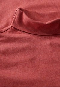 Vörös pamut szövet, textúrált felülettel és kiemelkedő gallérral, sima felülettel és finom kötött mintával az egész anyagon.
