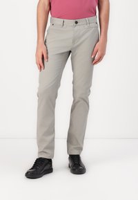 Pantalons en coton gris clair avec une coupe ajustée, dotés de poches avant, d'une fermeture à bouton et d'une texture lisse. Portés avec des baskets noires.
