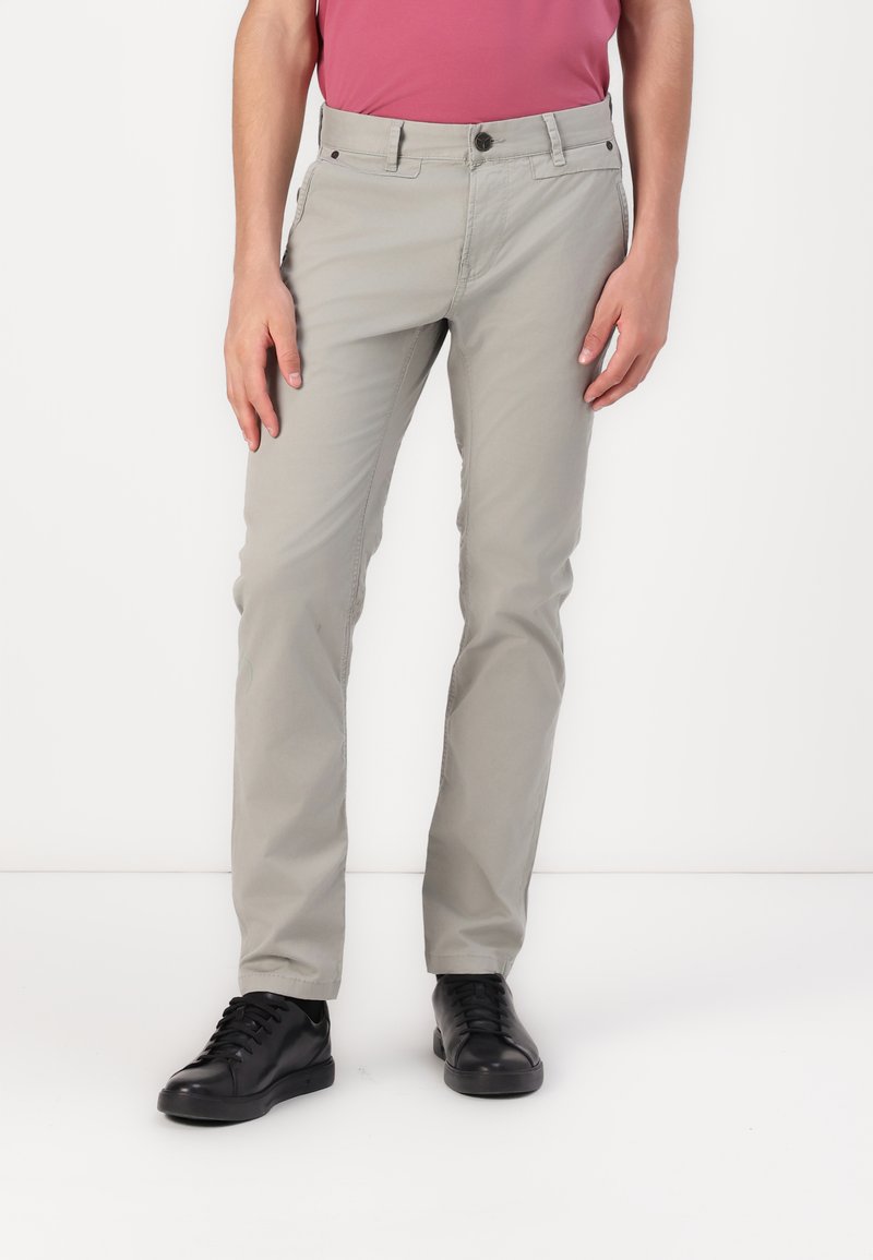 Pantalons en coton gris clair avec une coupe ajustée, dotés de poches avant, d'une fermeture à bouton et d'une texture lisse. Portés avec des baskets noires.