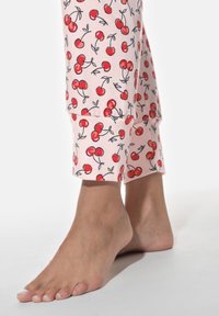 Ljusrosa pyjamasbyxor med körsbärsmönster, med en åtsittande passform vid anklarna. Mjuk bomullstyg och uppvikta ärmar.