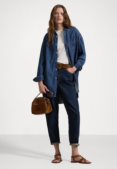 Camicia di denim, t-shirt bianca, pantaloni in denim scuro, cintura marrone, borsa marrone, sandali marroni. Vestibilità ampia, maniche arrotolate, outfit casual.
