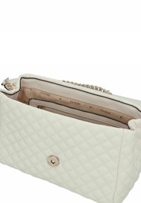 Bolso de mano de cuero sintético blanco acolchado con cadena, que presenta un cierre con cremallera, interior beige y un detalle con el logo.
