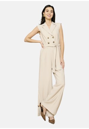 Beige double-breasted jumpsuit with a belted waist, wide-leg silhouette, and sleeveless design. Patterned high-heeled shoes are included.