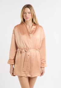 Jasnoróżowy satynowy szlafrok z długimi rękawami, miękkie futrzane akcenty na mankietach, pasek w talii, długość do kolan, gładka faktura, minimalistyczny styl.