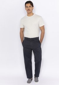 White textured short-sleeve shirt, dark blue trousers, and patterned slip-on shoes. Casual outfit with a relaxed fit and subtle details.