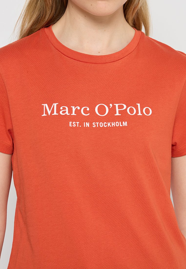 Rotes Baumwoll-T-Shirt mit kurzen Ärmeln und Rundhalsausschnitt. Mit weißem Text-Logo: "Marc O'Polo EST. IN STOCKHOLM" über die Brust gedruckt.