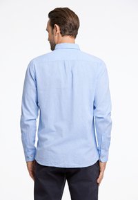 Lichtblauw langarm shirt van textuurstof, met een button-down kraag en enkele knopen bij de manchetten, met een rechte zoom aan de achterkant.