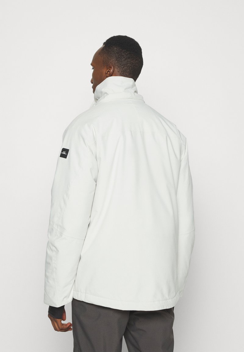 Weiße wasserdichte Jacke mit hohem Kragen, langen Ärmeln und einem Logo-Patch auf der linken Schulter. Glatte Textur mit geradem Schnitt.