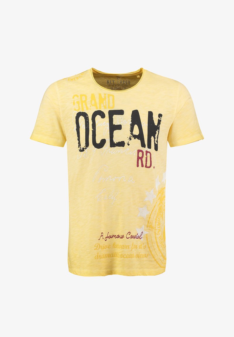 T-shirt gialla a maniche corte con grandi scritte nere e rosse, caratterizzata da un design testurizzato e accenti leggermente sbiaditi. Include grafica e motivi stilizzati.