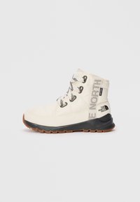 White insulated boot with black rubber sole, white laces, and "The North Face" branding. Features a padded collar and textured fabric.