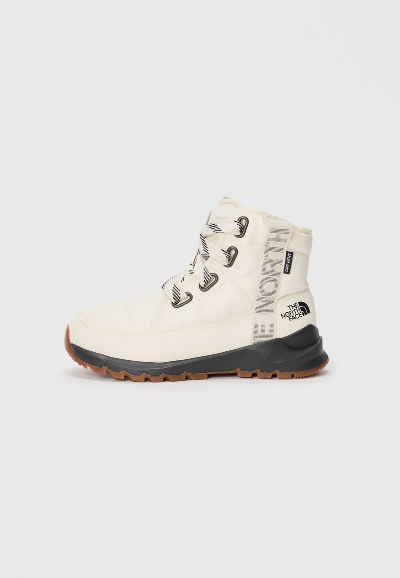 White insulated boot with black rubber sole, white laces, and "The North Face" branding. Features a padded collar and textured fabric.