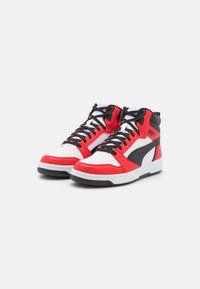 Czerwone, białe i czarne sneakersy typu high-top wykonane z syntetycznej skóry. Posiadają perforowany czubek, czarne sznurówki oraz wyraźne logo po boku.