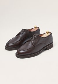 Braune Lederdressschuhe mit glatter Textur, runder Zehenform und klassischem Schnürdesign. Enthält einen Holzschuhspanner und gestickte Details.