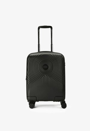 Valigia rigida nera con texture a onde, manico retrattile e quattro ruote per la mobilità. Chiusura con zip nella parte superiore.