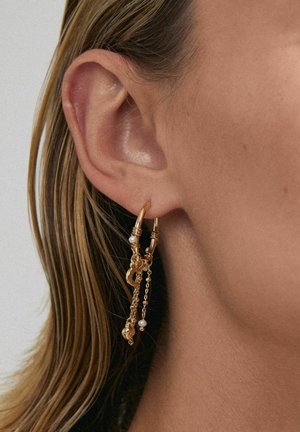 Gold hoop earring with chained accents, featuring small white pearls and decorative elements, set against a neutral background.