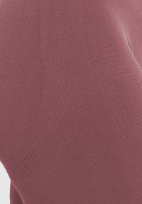 Rode textiel met een gestructureerde stof, met ribbelpatronen. Zacht, rekbaar materiaal met een gladde afwerking en subtiele glans, ontworpen voor comfort en pasvorm.