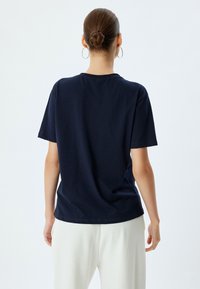 Camiseta de algodón azul marino de manga corta, con cuello redondo y un corte relajado. Sin patrones ni gráficos visibles. Vista trasera únicamente.