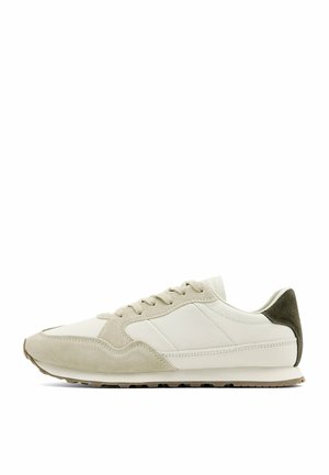 Lavprofil beige og hvid sneaker med ruskindsoverlejringer, snørelukning og mørkebrun hælaccents på en hvid baggrund.