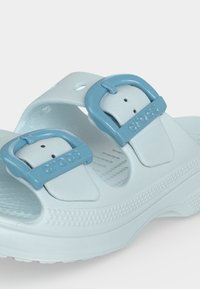 Σανδάλι Crocs σε ανοιχτό μπλε χρώμα με δύο ρυθμιζόμενες αγκράφες και υφασμένο πάτο σχεδιασμένο για άνεση και καθημερινή χρήση.