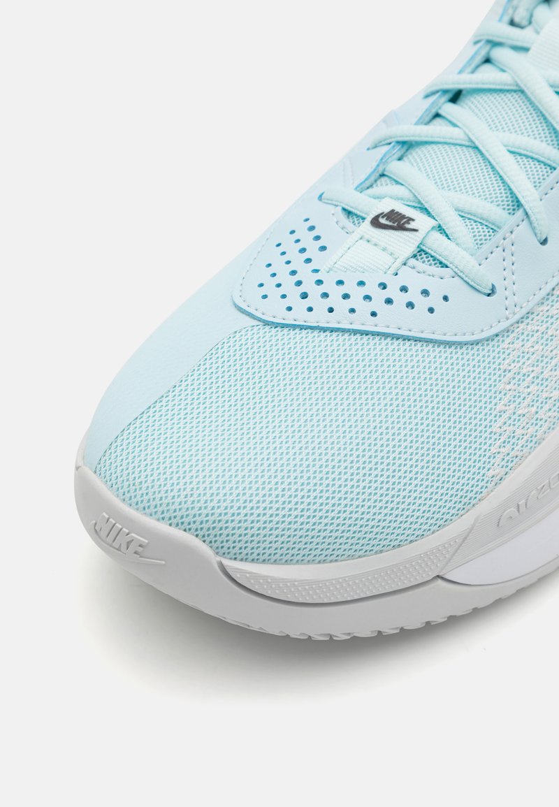 Jasnoniebieski but sportowy z siateczkową cholewką, perforowanymi detalami, płaskimi sznurówkami i szarym podbiciem z logo Nike po boku.