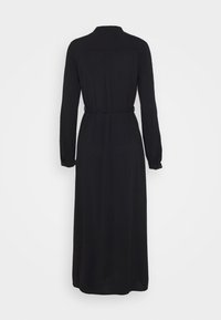 Svart långärmad klänning med bälte, som har en rak silhuett, mjukt tyg och en urklippt krage. Bakifrån syns veckdetaljer.