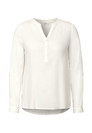 Blusa bianca a maniche lunghe con scollatura a V e abbottonatura frontale, dotata di un orlo leggermente curvo e polsini arrotolati. Realizzata in tessuto morbido.