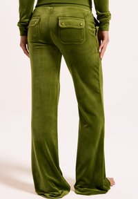 Zelene velur hlače z ohlapnim krojem, ki imajo dva zadnja žepa z zlatimi kovinskimi detajli in gladko teksturo.