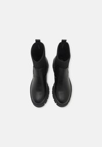 Black leather ankle boots with chunky soles and ribbed knit elastic panels, viewed from above on a white background.