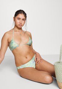 Biquíni floral com um top triangular e parte de baixo de cintura alta nas tonalidades verde, azul e branca, feito de um tecido liso e elástico.