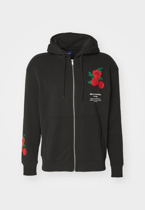 Sweat à capuche noir zippé en tissu doux, avec une broderie de rose rouge sur le devant et les manches, et une poche avant.