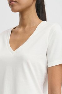 White cotton t-shirt with a v-neck design and short sleeves, featuring a soft texture and minimalistic style.