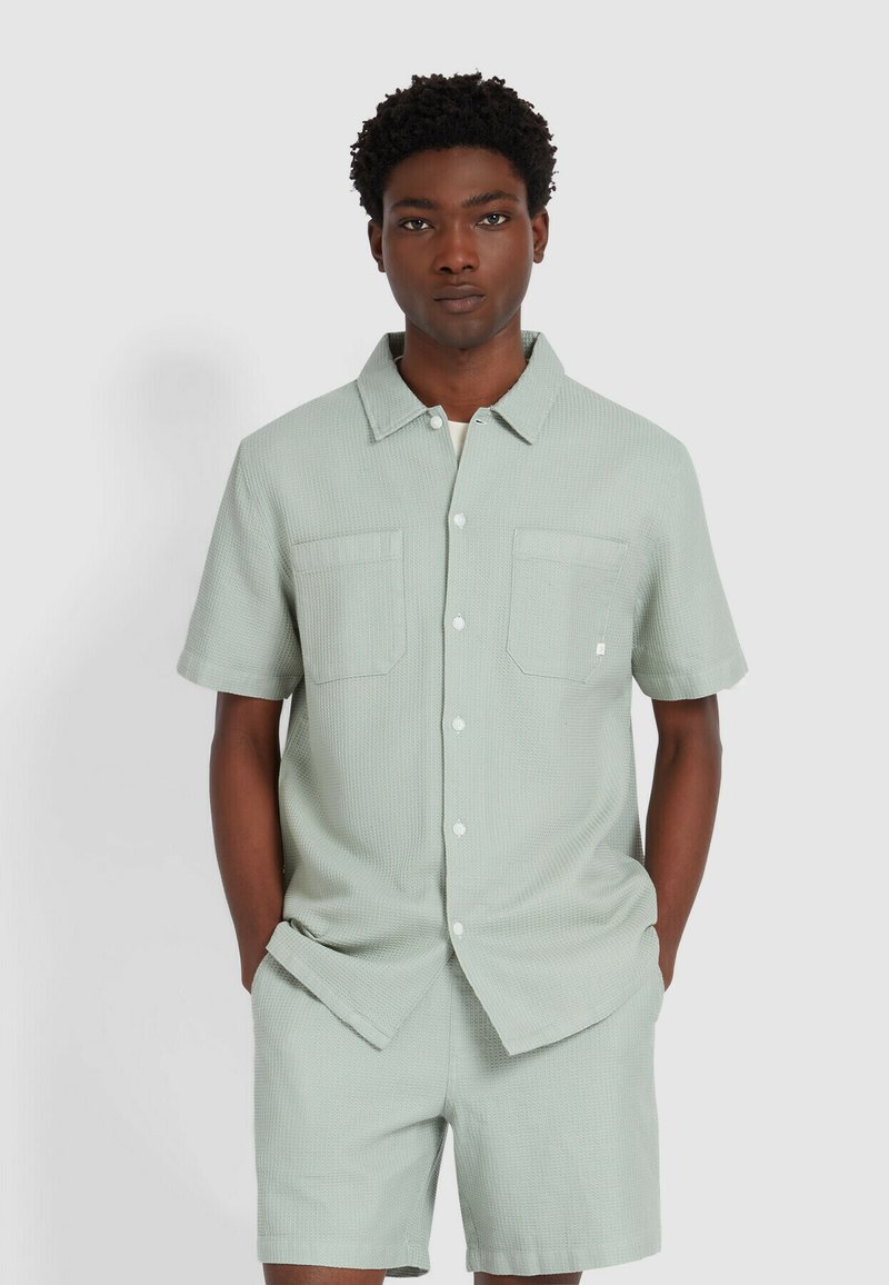 Korte mouw, knoopsluiting shirt in lichtgroene, gestructureerde stof met twee voorzakken, gecombineerd met bijpassende shorts. Beide stukken hebben een relaxte pasvorm.