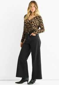 Leopard print long-sleeve top with a V-neck, paired with high-waisted wide-leg black jeans and pointed black ankle boots.