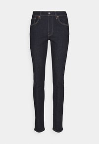 Jeans vaqueros de denim azul oscuro con un ajuste slim, diseño de cinco bolsillos, costuras visibles y cierre de botones.