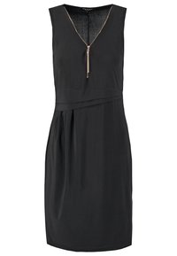 Robe noire sans manches avec col en V, fermeture éclair à l'avant avec pompon et détail asymétrique à la taille. Longueur genou, tissu lisse.